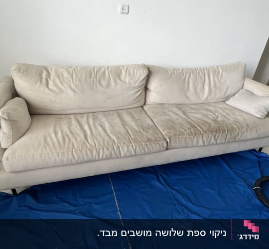 ספה בהירה עם כתמים על יריעת בד כחולה